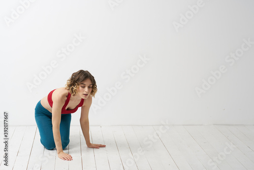 A woman in blue jeans practices yoga on a light background indoors and a slim figure in gymnastics © SHOTPRIME STUDIO