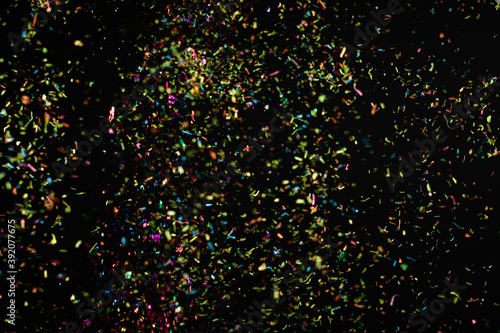 Multicolored confetti falling against black background