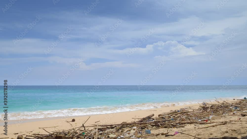 Tropical beach with beautiful vibrant blue water, wooden and plastic garbage and waste on yellow sand Tropical beach with beautiful vibrant blue water, wooden and plastic garbage and waste on yellow sand