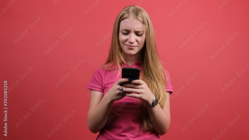 Portrait of a surprised confused woman chatting online with friends, isolated over red background. Portrait of a surprised confused woman chatting online with friends, isolated over red background.