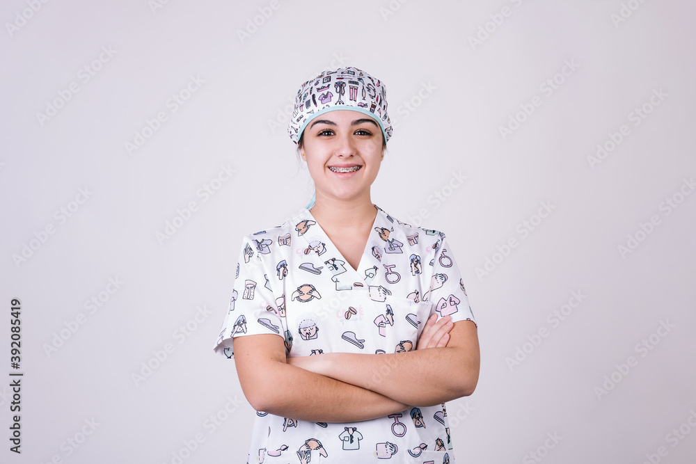 female nurse dressed in uniform of figures related to the profession. She looks happy and smiling at the camera while crossing her arms. female nurse dressed in uniform of figures related to the profession. She looks happy and smiling at the camera while crossing her arms.