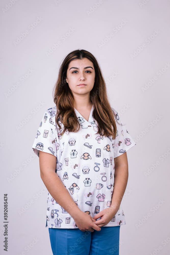 portrait of a female nurse looking serious. She is wearing a very colorful figure uniform. Her hair is brown and long portrait of a female nurse looking serious. She is wearing a very colorful figure uniform. Her hair is brown and long