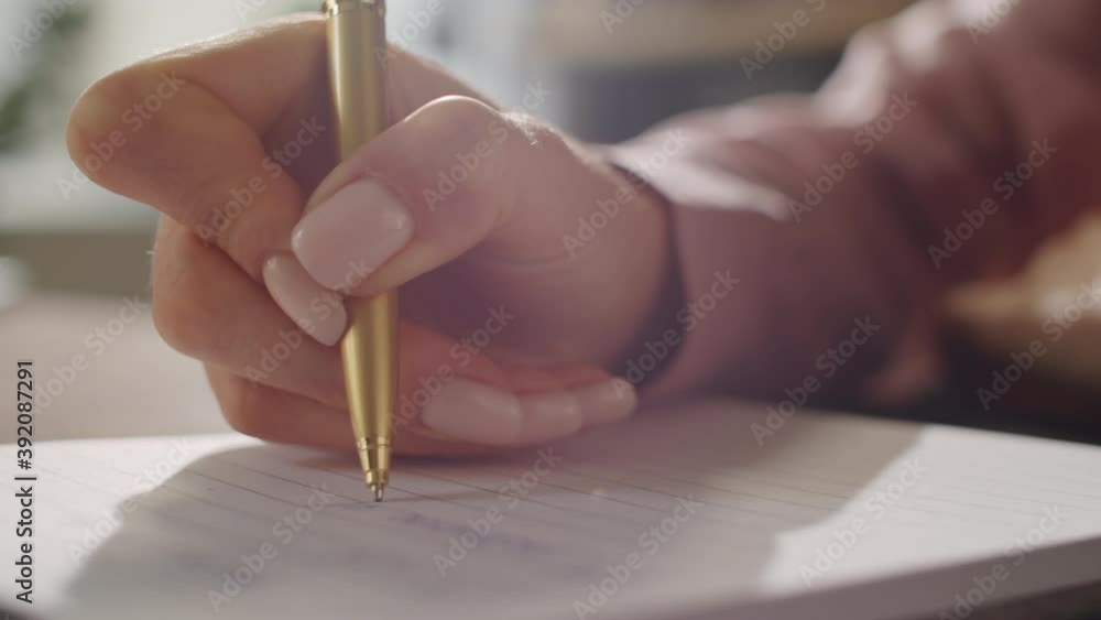 Close up view of hand of unrecognizable businesswoman writing on paper at desk during workday
