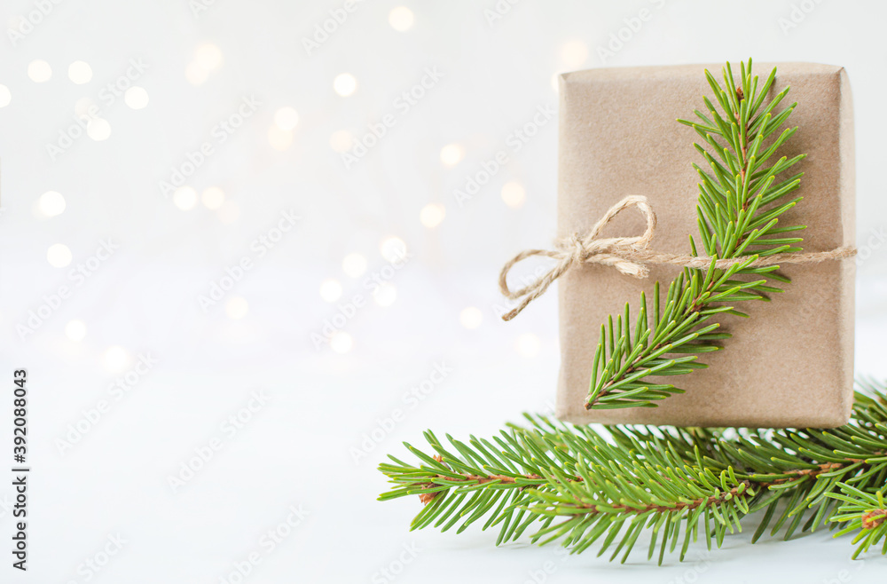 branch spruce and gift in craft paper on light background with bokeh