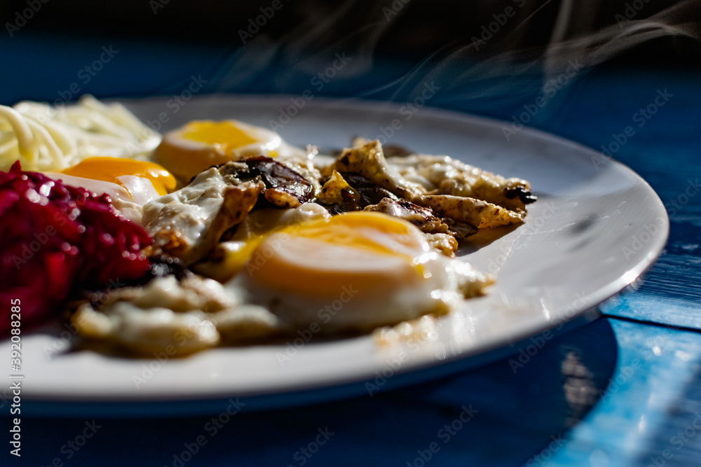 Fried eggs with mushrooms, long cheese noodles and beetroot caviar, a hearty fried dish for Breakfast with appetizers. The flowing liquid yellow egg yolk Fried eggs with mushrooms, long cheese noodles and beetroot caviar, a hearty fried dish for Breakfast with appetizers. The flowing liquid yellow egg yolk