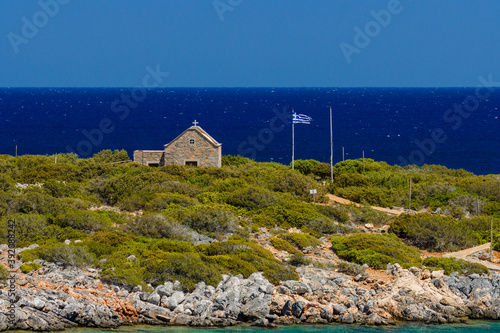 Small Greek church next to a crystal clear, warm sea photo