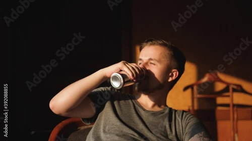 Lazy handsome bearded man drinks beer on couch. slow motion