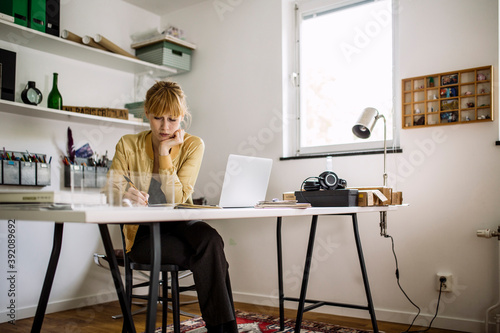 Woman thinking at desk in home office
