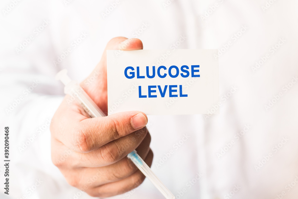 Word glucose level on a white background with a syringe in hand. Medicine concept Word glucose level on a white background with a syringe in hand. Medicine concept