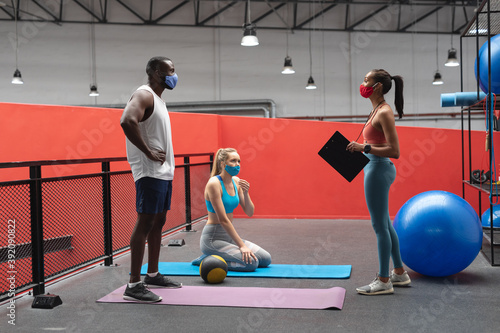  caucasian female fitness trainer holding stopwatch and clipboard instructing fit african american m photo