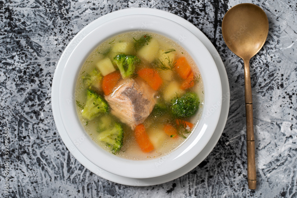 Fresh salmon fish soup with carrots, potatoes and onions in a white plate, close up. Top view Fresh salmon fish soup with carrots, potatoes and onions in a white plate, close up. Top view