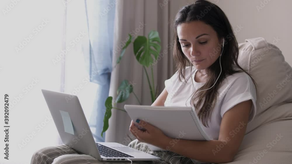 Young woman wears headset online teacher studying from laptop, working from home. Lady student learning using computer webcam chat makes notes. Distance education concept Young woman wears headset online teacher studying from laptop, working from home. Lady student learning using computer webcam chat makes notes. Distance education concept