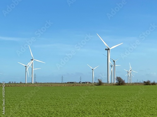Wind turbines that produce electricity energy. Windmill Wind power technology productions Wind turbines standing on a blooming fields in green field. 