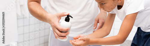 Wallpaper Mural Man squeezing liquid soap on hand of boy leaning forward in bathroom, banner Torontodigital.ca