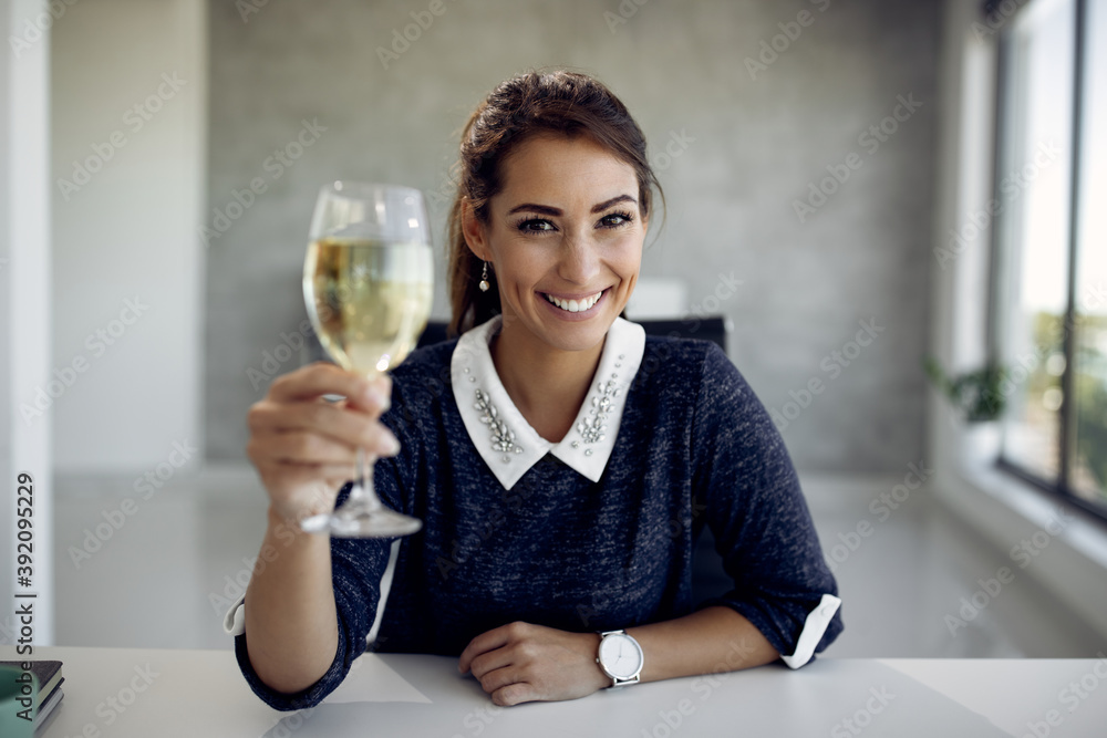 Young happy businesswoman toasting with wine in the office. Young happy businesswoman toasting with wine in the office.