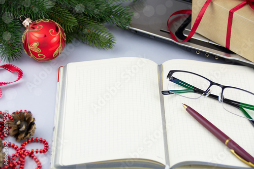 Open blank notepad on the desk with laptop, gft box and Christmas decoration photo