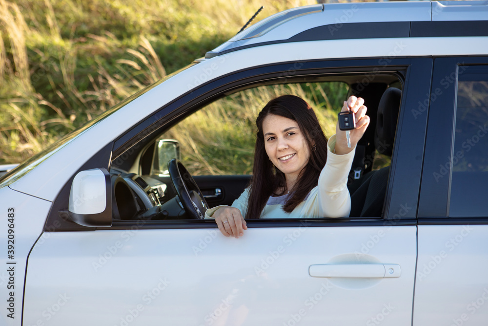 pretty woman sitting in car and showing keys