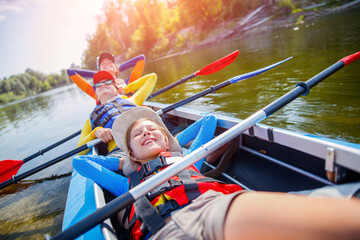 Happy kids kayaking on the river on a sunny day during summer vacation