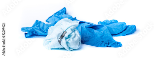 used surgical mask and blue latex surgical gloves on white background. the problem of disposal of medical waste and environmental pollution. End of quarantine. Covid-2019.