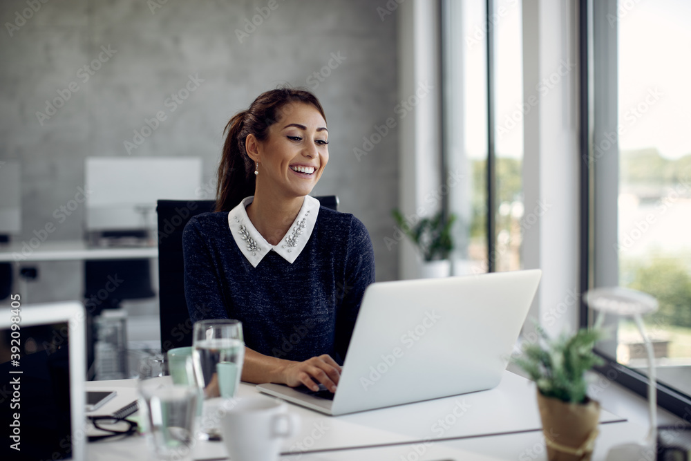 Young happy businesswoman working on laptop in the office. Young happy businesswoman working on laptop in the office.