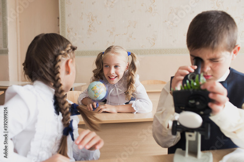 the concept of education, science and children - children or students with a microscope study biology in the school laboratory