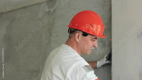 The worker is leveling the wall with a tool indoors
