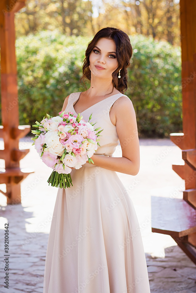 Portrait of merciful bride standing with wedding bouquet. Brunette at photoshoot in park Portrait of merciful bride standing with wedding bouquet. Brunette at photoshoot in park