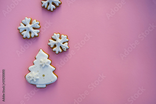 Christmas gingerbreads in the form of trees and snowflakes on a pink background. Composition with empty space for text; top view, flat lay.