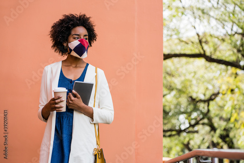 Business woman holding digital tablet and coffee outdoors.