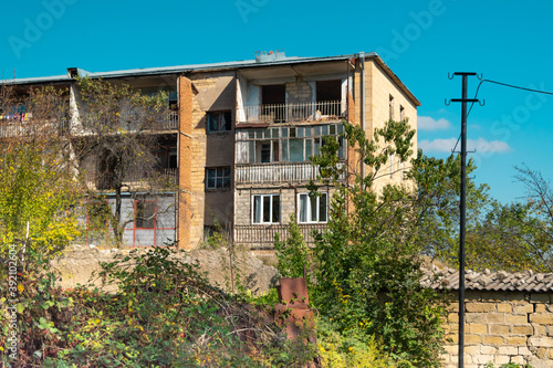 Building at Sushi (Shusha) in Nagorno Karabakh in very poor condition with vegetation growing wild on the street photo