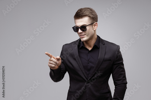 Portrait of beautyful smiling guy on gray background. High fashion model posing in studio. Attractive man in classic suit.