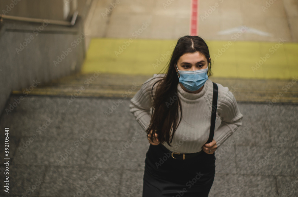 mujer joven con mascarilla en una estación de metro