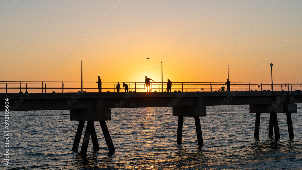 Pier with fishermen at sunset on Masirah Island in Oman