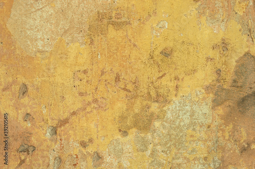 A large fragment of the yellow clay wall of the old house with cracks and roughness, exfoliating part of the plaster. Vintage background. Rough flushed texture. Space to copy text.