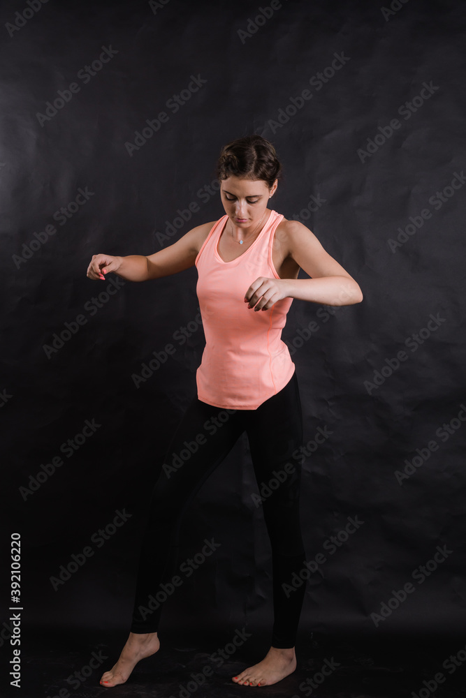Beautiful young woman dressed in sportswear studio portrait on black background.
