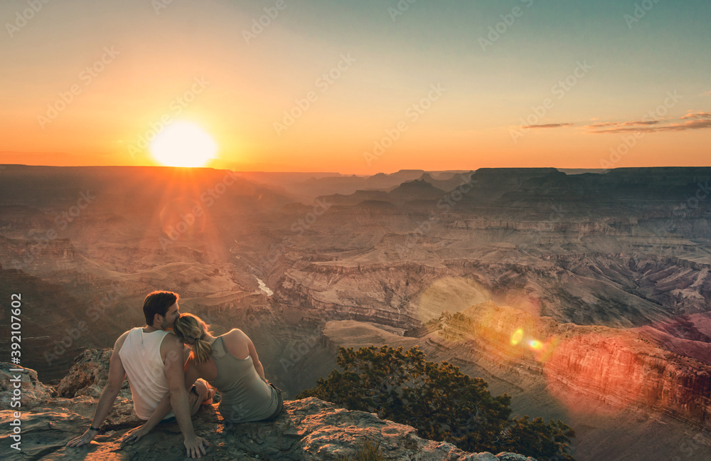 Paar sitzt am Rand des Grand Canyons bei Sonnenuntergang.