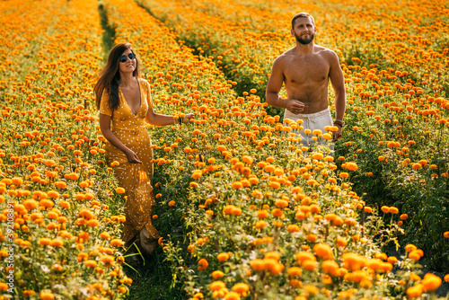 Couple in love on a flower field. A beautiful couple runs through a flower field. Man and woman in the flower fields. Yellow flower field. Happy couple. Copy space.