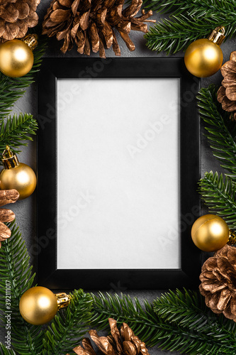 Christmas composition with empty picture frame. Golden ornament, pine cones and fir needles decorations. Mock up greetings card template