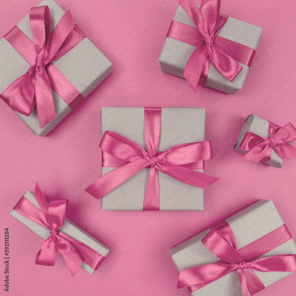 Gift boxes wrapped in craft paper with soft pink ribbons and bows. Festive monochrome flat lay.
