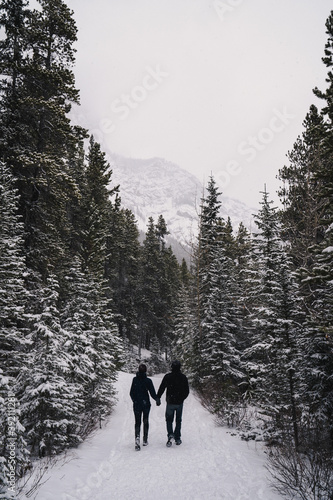 Couple Walking in Snow Hand-In-Hand Along Mountain Trail 