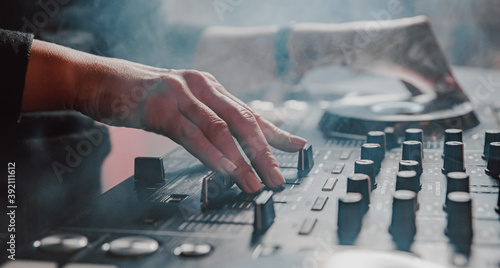 Fotografie DJ Hands creating and regulating music on dj console mixer in concert nightclub