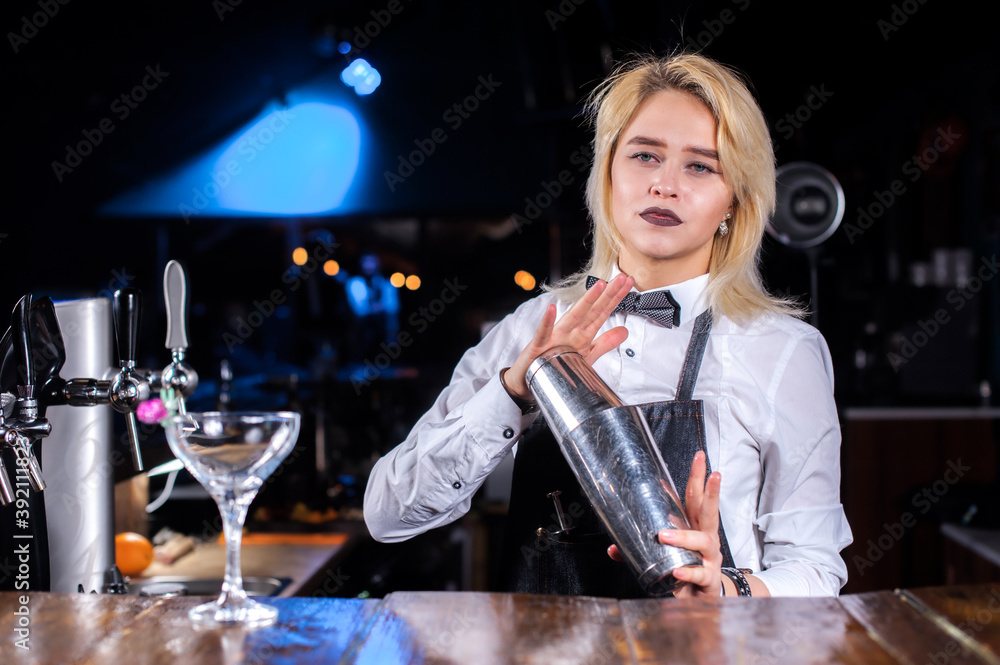 Expert girl barman demonstrates the process of making a cocktail in the pub