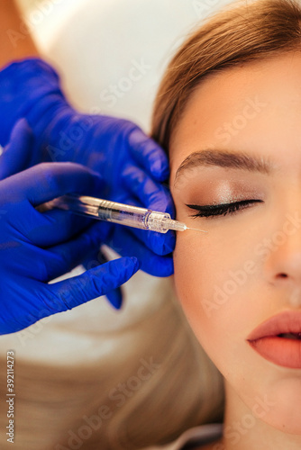 Beautiful woman gets an injection in her face. she has fashion make up and red shining lips