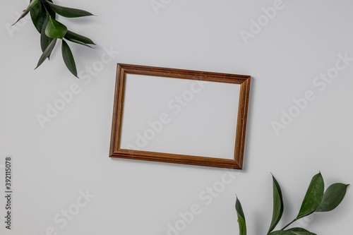 Empty brown wood border, with craft paper and green branches isolated on white table background. © Pavel Korotkov