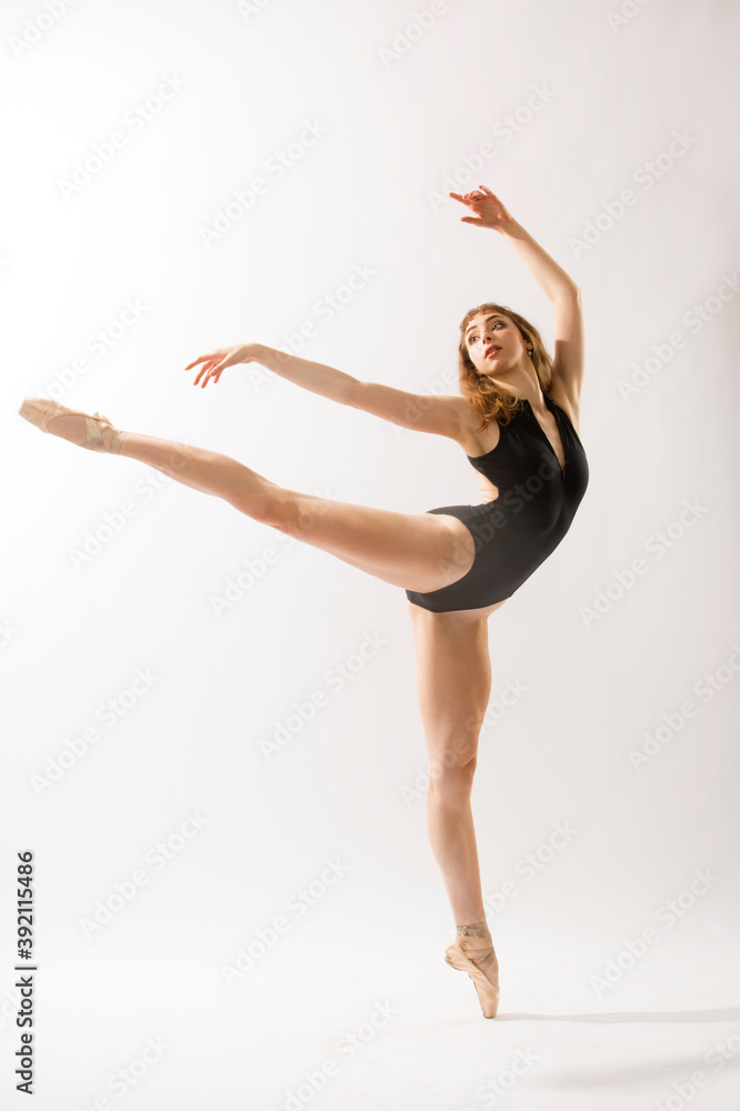 Fototapeta premium Ballerina in black leotard, dancing against a white background.