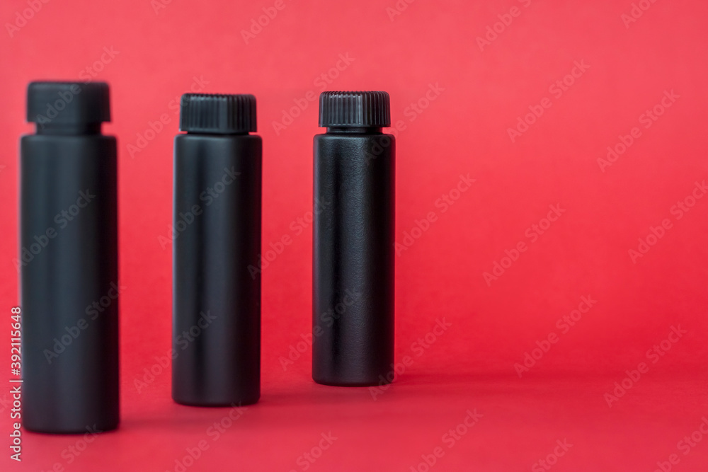 Black bottles with cream on a red background. Skin care, Moisturizing and nourishing or sunscreen. Black bottles with cream on a red background. Skin care, Moisturizing and nourishing or sunscreen.