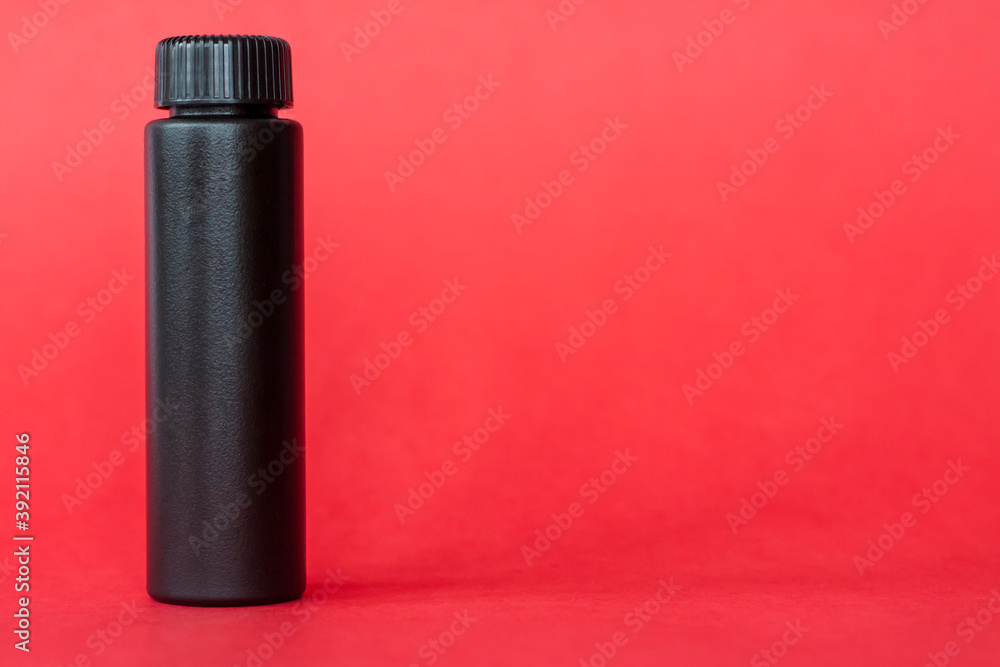 Black bottle with cream on a red background. Skin care, Moisturizing and nourishing or sunscreen.