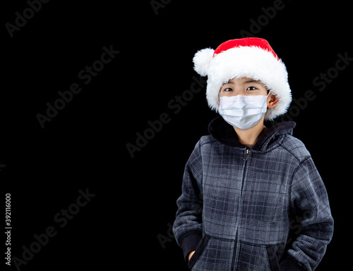 Boy Wearing Santa Hat and Face Mask During Covid-19 Christmas Pandemic With Copy Space © ronniechua