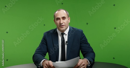 Male newsanchor informing about current news. Professional television live reporter talking about recent global events in business and politics. Chroma key green background 4k footage photo