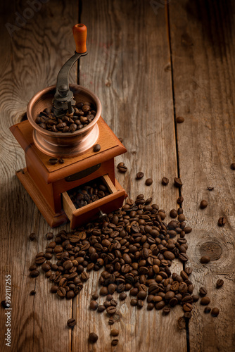Coffee grinder with coffee beans over wood